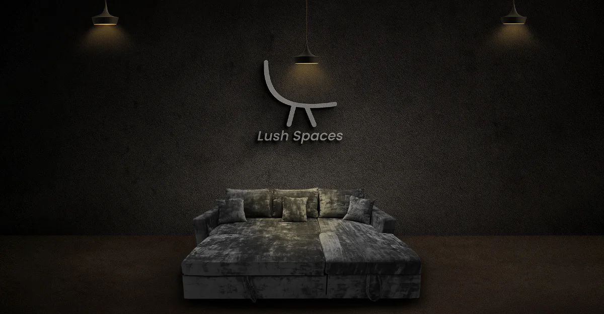 A neatly made sofa cum bed with a white sheet and a wall-mounted lamp illuminating the space.